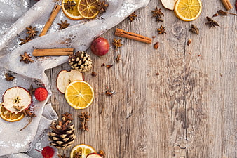 Christmas spices, dried fruits, and pinecones on rustic wood