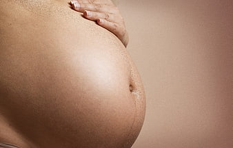 Close-up of pregnant woman's belly with hand