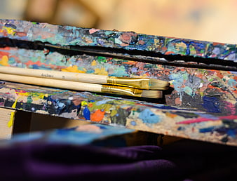 Close-up of paintbrushes on a colorful wooden artist palette