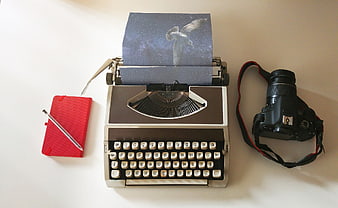 Vintage typewriter with galaxy bird photo and camera on white desk