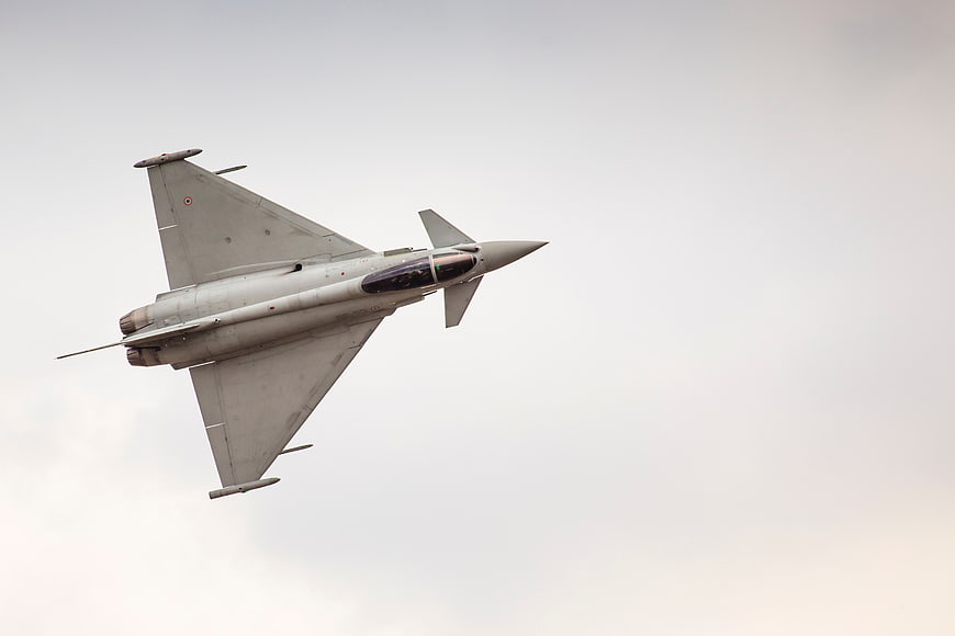 Gray Military Fighter Jet Flying Against Overcast Sky