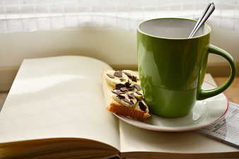 Green coffee mug and banana toast on open book