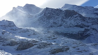 Snowy Swiss Alps mountain landscape with wind and clouds