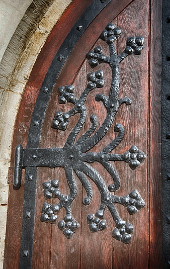 Close-up of ornate wrought iron hinge on wooden church door