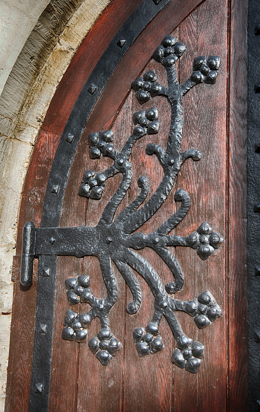 Close-up of ornate wrought iron hinge on wooden church door