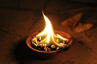 Traditional clay diya lamp with bright flame on dark background