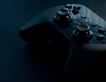 Close-up of black video game controller on dark textured surface