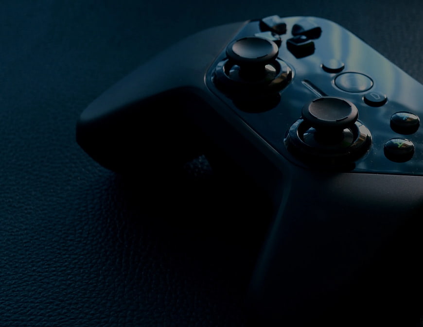 Close-up of black video game controller on dark textured surface