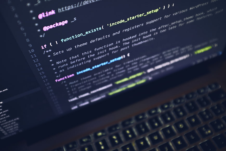 Close-up of PHP code on laptop screen with blurred keyboard