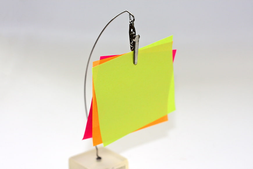 Colorful sticky notes clipped to a metal stand on white background
