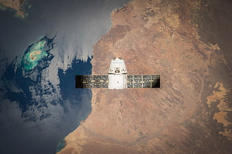 SpaceX Dragon spacecraft orbiting Earth over desert coastline