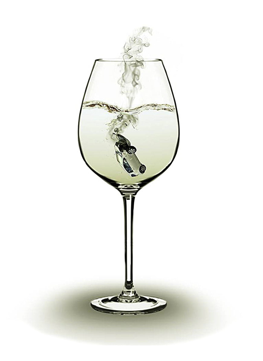 Miniature car sinking in wine glass with smoke