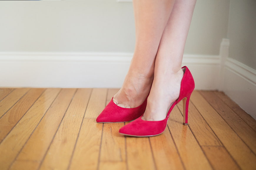 Woman's Legs in Red Suede High Heels on Wooden Floor