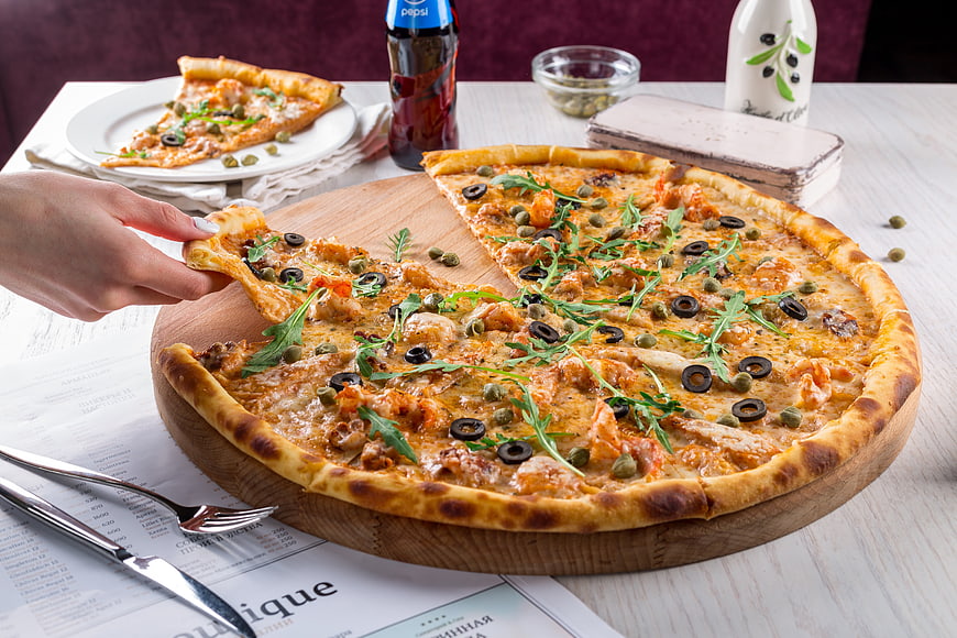 Delicious Pizza with Olives and Arugula on Wooden Board