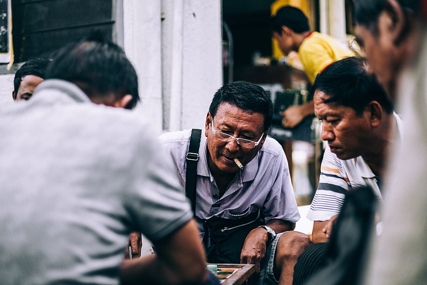 Men playing chess on street with cigarette