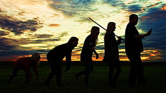 Silhouetted Group Reenacting Human Evolution Stages at Sunset