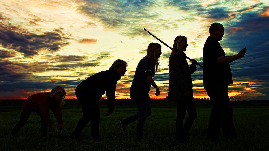 Silhouetted Group Reenacting Human Evolution Stages at Sunset