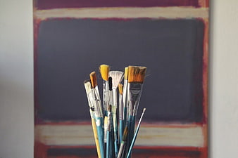 Collection of Paint Brushes in Front of Abstract Art