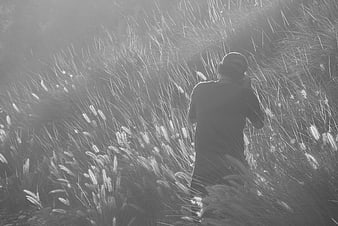 Man taking photo in tall grass black and white