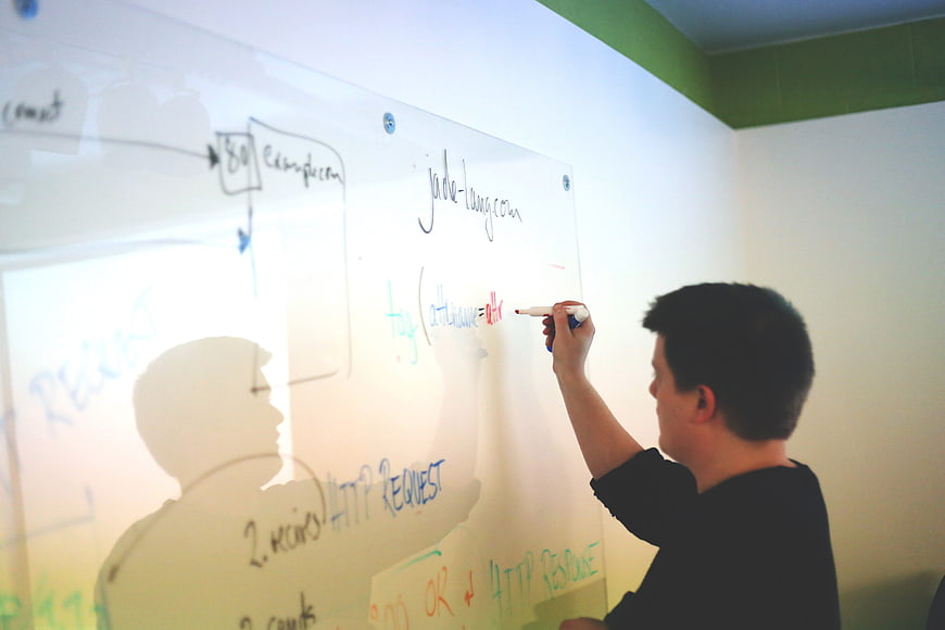 Man writing technical diagram on whiteboard in office