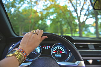 Woman's hand on steering wheel with watch and rings