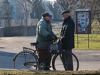 Two elderly men talking with bicycle in park