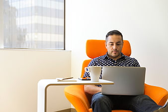 Man working on laptop in orange office chair