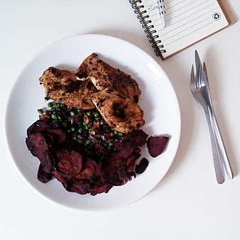 Top view of grilled chicken breast with roasted beets and peas