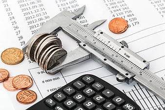 Vernier caliper measuring stack of coins on financial spreadsheet