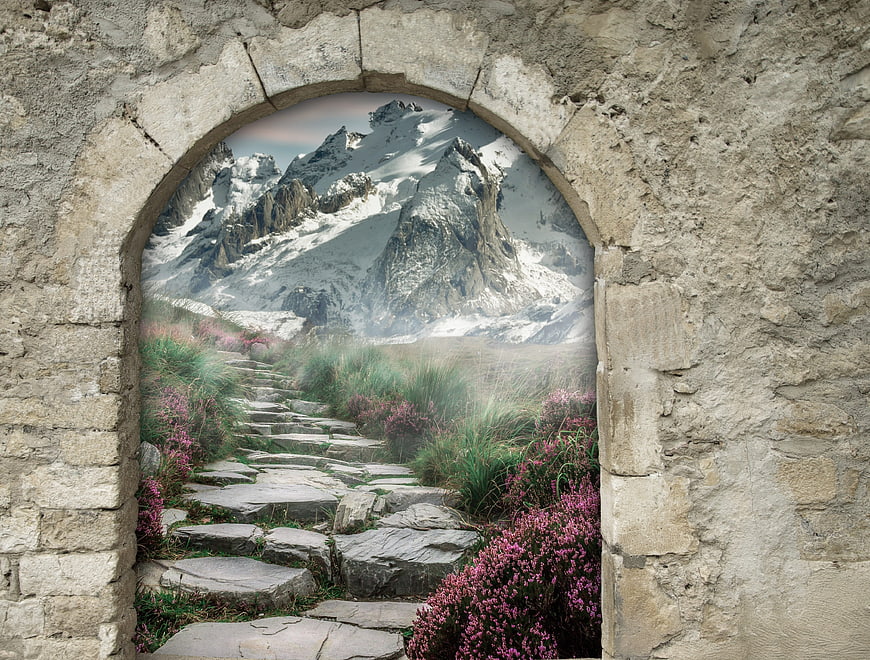 Stone archway framing a magical mountain path with pink flowers