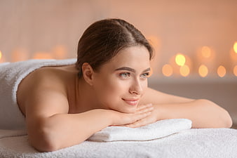 Relaxed Woman Lying on Spa Table with Candles