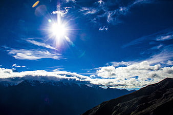 Sunburst Over Snow-Capped Mountain Ranges And Clouds