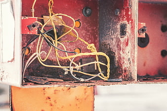 Rusty electrical box with tangled yellow and black wires