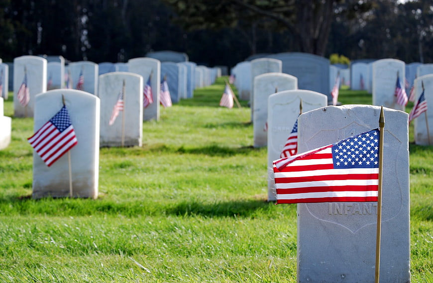 American flags on white headstones in a military cemetery