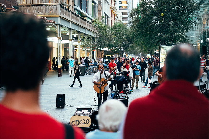 Street musician performing guitar for crowd in city