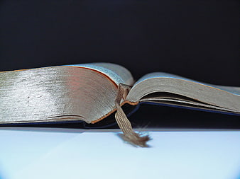 Close-up of open book with bookmark on white surface