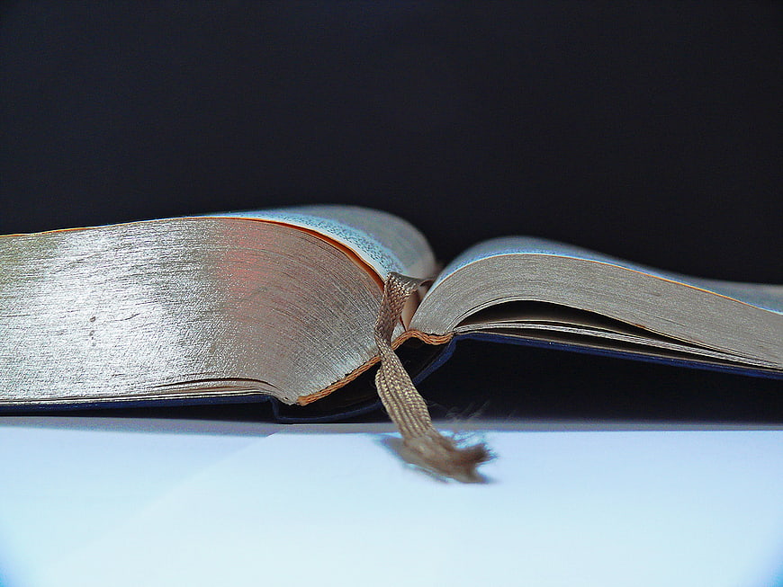 Close-up of open book with bookmark on white surface