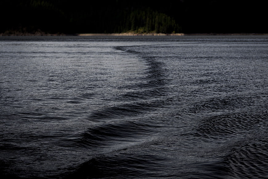 Dark rippling water surface with distant forest shoreline