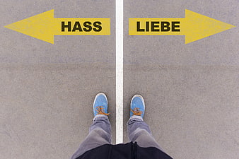First person view of feet standing on road with arrows pointing to Hass and Liebe