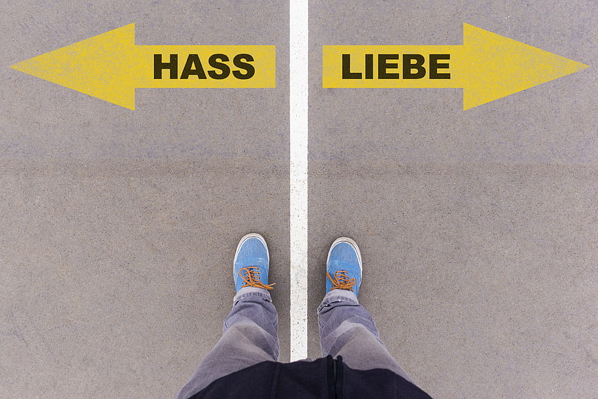 First person view of feet standing on road with arrows pointing to Hass and Liebe