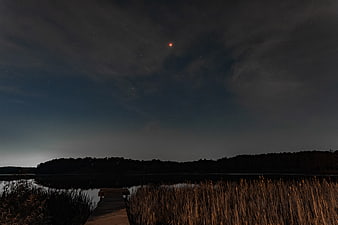 Total Lunar Eclipse Over Lake With Wooden Dock