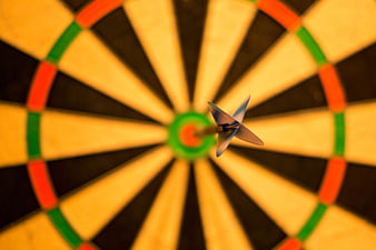 Dart hitting bullseye on dartboard close up