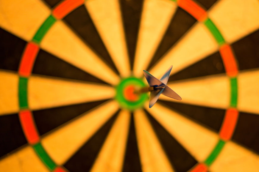 Dart hitting bullseye on dartboard close up