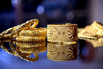 Luxury Gold Bangles and Jewelry on Reflective Surface