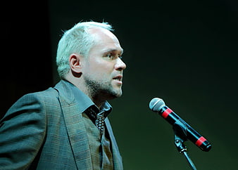 Man Speaking Into Microphone On Stage