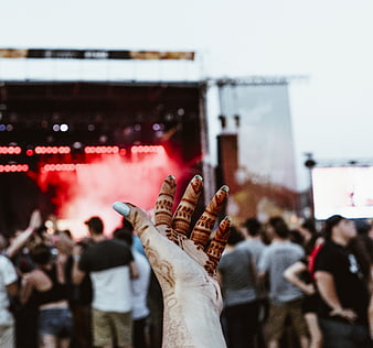 Hand with henna raised at outdoor music festival