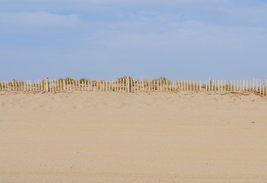 Wooden Beach Fence on Sand Dune with Blue Sky