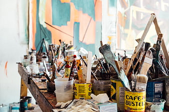 Cluttered artist workspace with paint brushes and supplies