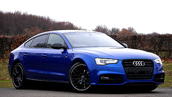 Blue Audi A5 Sportback parked on a road with autumn trees in the background