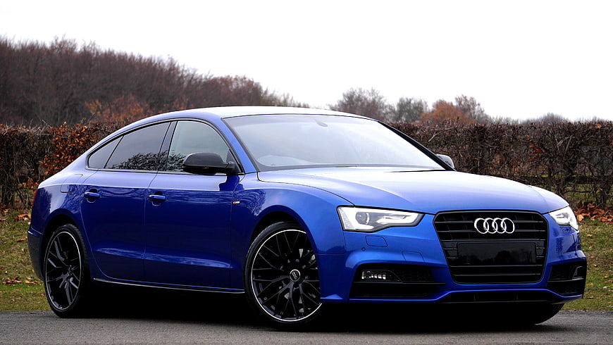 Blue Audi A5 Sportback parked on a road with autumn trees in the background